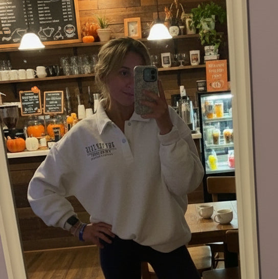 Person wearing a white sweatshirt with text in a room with purple walls.